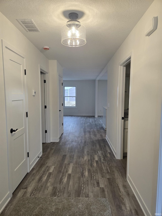 hall with dark wood-type flooring and a textured ceiling