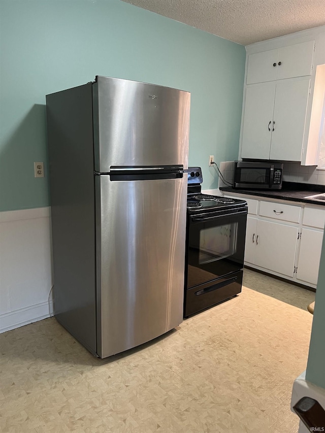 kitchen with sink, stainless steel refrigerator, white cabinetry, a textured ceiling, and black / electric stove