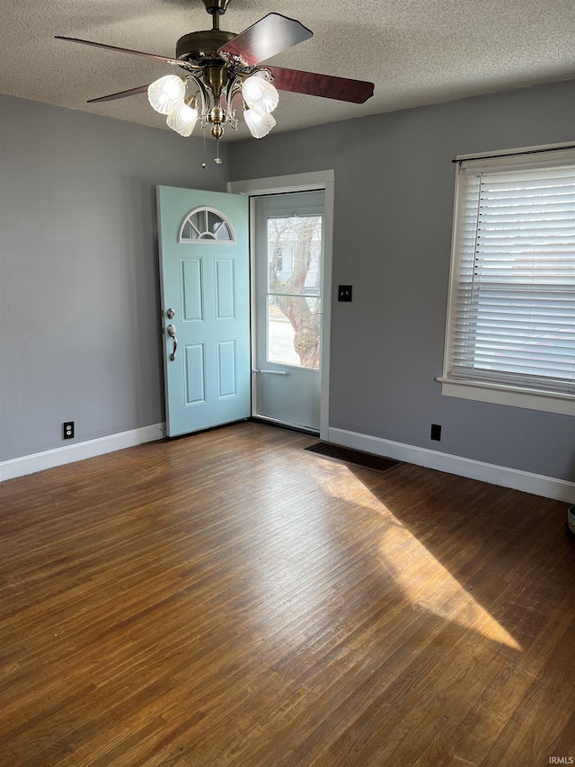 foyer featuring dark hardwood / wood-style flooring, ceiling fan, and a textured ceiling