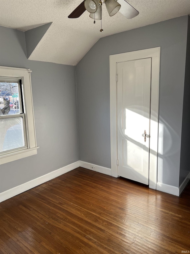 interior space with vaulted ceiling, ceiling fan, a textured ceiling, and dark hardwood / wood-style flooring