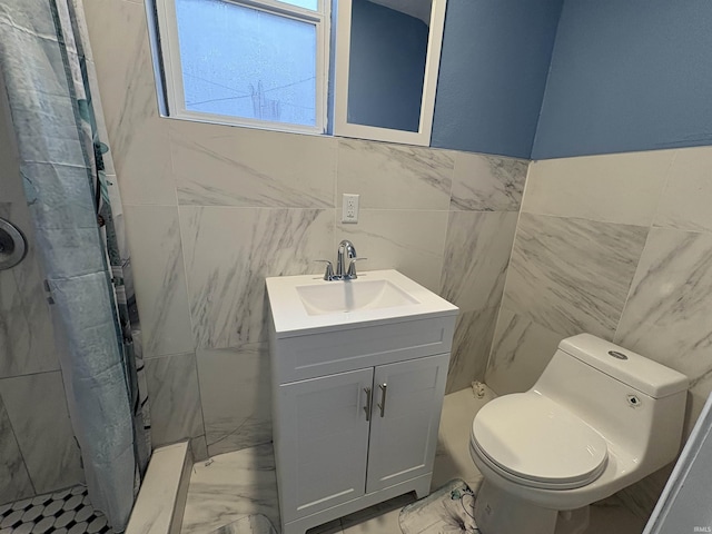 bathroom with vanity, a tile shower, tile walls, and toilet