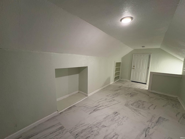 bonus room featuring lofted ceiling, a textured ceiling, and built in shelves