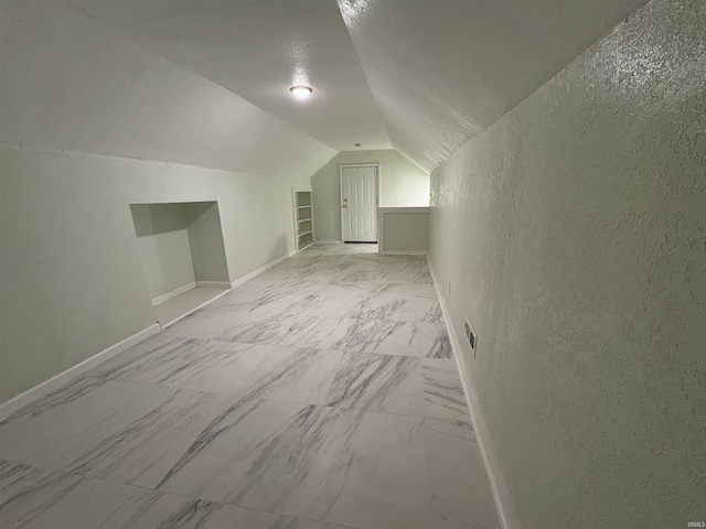 bonus room with vaulted ceiling, built in features, and a textured ceiling