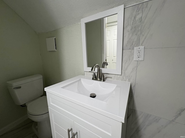 bathroom featuring lofted ceiling, vanity, and toilet