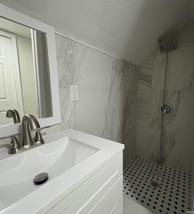 bathroom with vanity, tile walls, a textured ceiling, and a tile shower