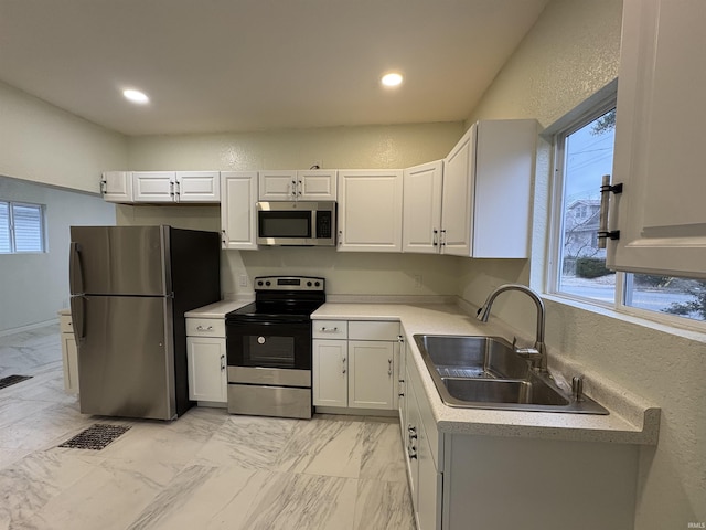 kitchen featuring a healthy amount of sunlight, appliances with stainless steel finishes, sink, and white cabinets