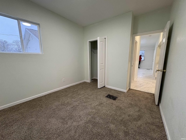 unfurnished bedroom featuring dark carpet and a closet