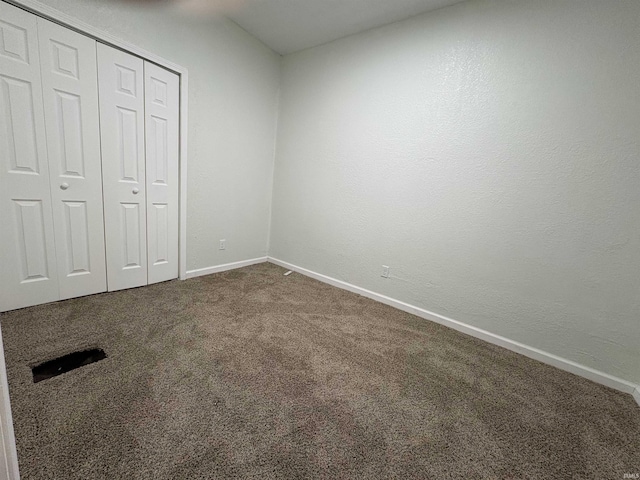 unfurnished bedroom with dark carpet and a closet