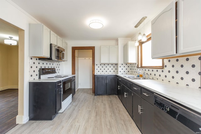 kitchen featuring sink, white cabinetry, tasteful backsplash, decorative light fixtures, and appliances with stainless steel finishes