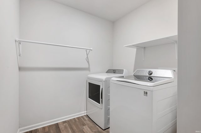 clothes washing area with washing machine and dryer and dark wood-type flooring