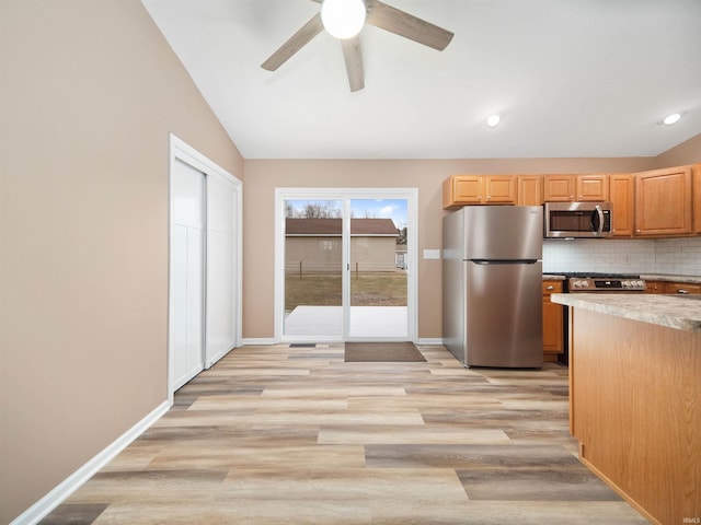 kitchen with tasteful backsplash, appliances with stainless steel finishes, lofted ceiling, and light hardwood / wood-style floors