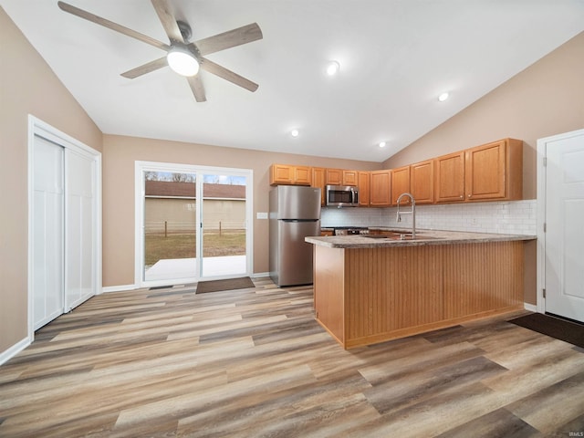 kitchen with appliances with stainless steel finishes, lofted ceiling, backsplash, and kitchen peninsula