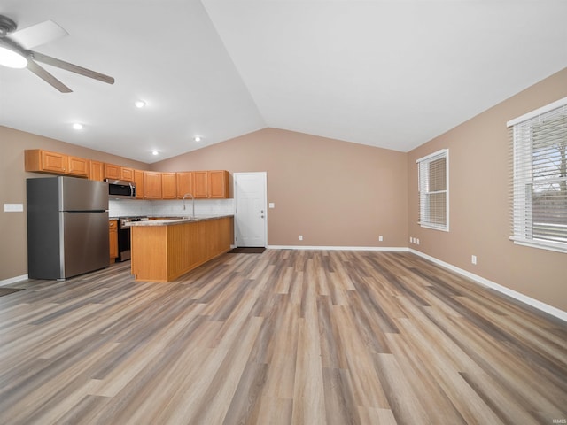 kitchen featuring lofted ceiling, appliances with stainless steel finishes, sink, and light hardwood / wood-style flooring