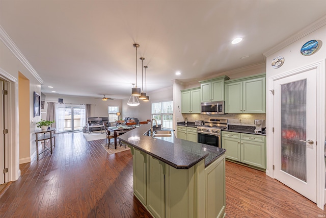 kitchen with sink, green cabinetry, decorative light fixtures, a center island with sink, and appliances with stainless steel finishes