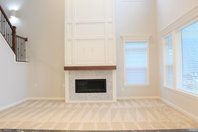 unfurnished living room with a towering ceiling and light colored carpet