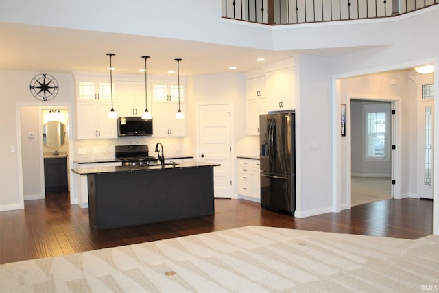 kitchen featuring pendant lighting, white cabinetry, backsplash, a kitchen island with sink, and stainless steel appliances