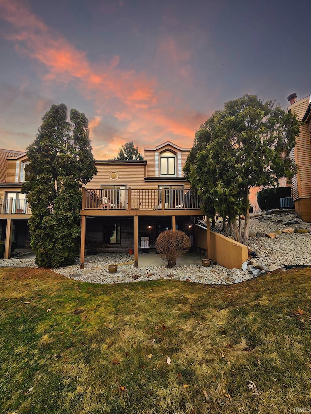 back house at dusk featuring a yard, a patio area, and a deck