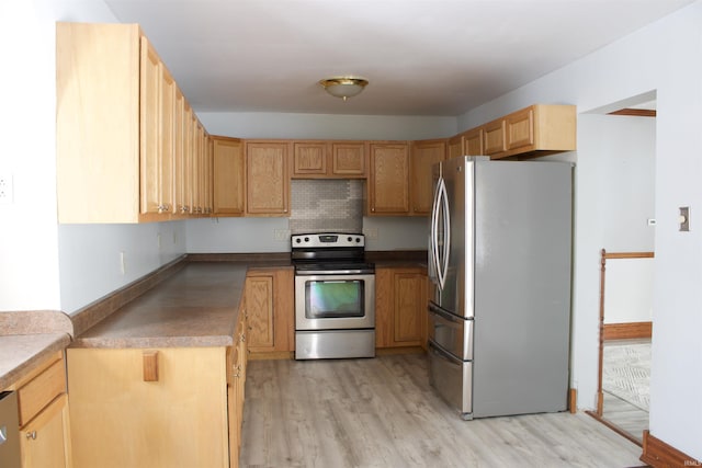 kitchen with light wood finished floors, tasteful backsplash, dark countertops, appliances with stainless steel finishes, and light brown cabinetry