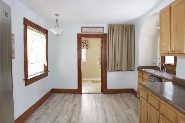 kitchen with dark countertops, hanging light fixtures, light wood-style floors, a sink, and dishwasher