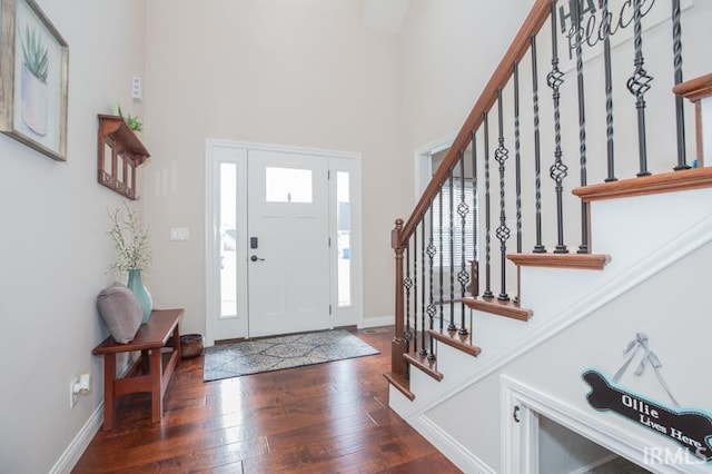 foyer featuring a towering ceiling and dark hardwood / wood-style floors