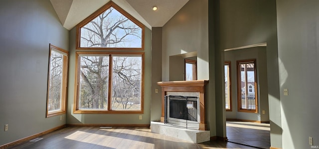 unfurnished living room featuring hardwood / wood-style flooring, a premium fireplace, and high vaulted ceiling