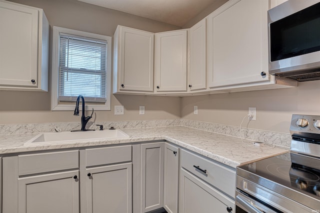 kitchen with stainless steel appliances, white cabinetry, and a sink