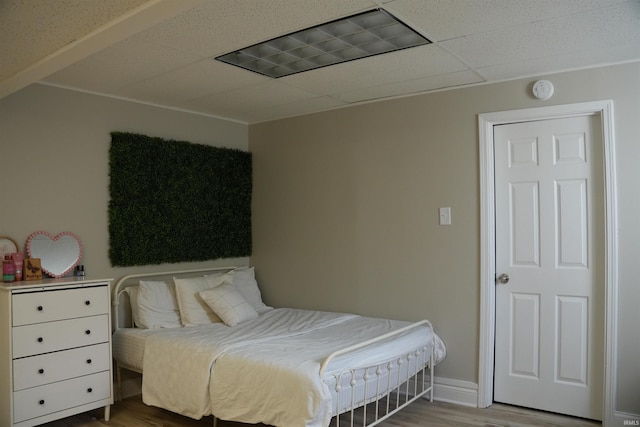 bedroom featuring hardwood / wood-style flooring and a drop ceiling