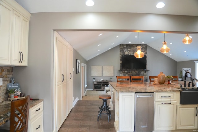 kitchen with lofted ceiling, a breakfast bar, sink, pendant lighting, and light stone countertops