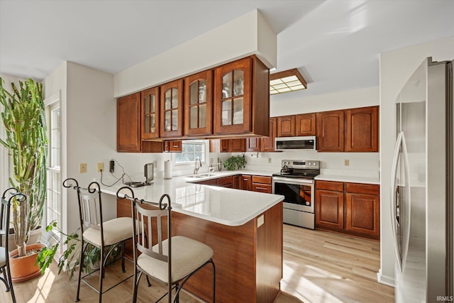 kitchen with sink, light hardwood / wood-style flooring, stainless steel appliances, and kitchen peninsula