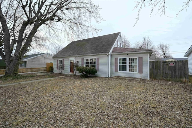 cape cod-style house with a shingled roof and fence