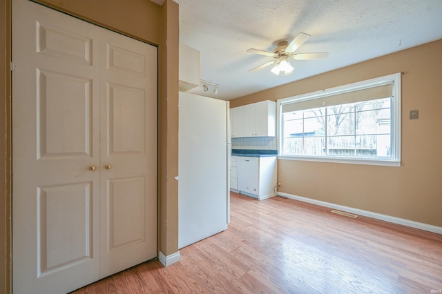 unfurnished bedroom with light wood-style floors, a closet, visible vents, and a textured ceiling