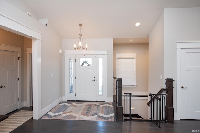 foyer entrance with vaulted ceiling, dark hardwood / wood-style floors, and a chandelier