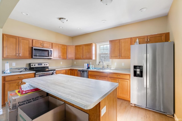 kitchen featuring stainless steel appliances, a center island, sink, and light wood-type flooring