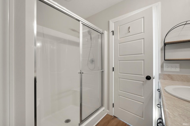 full bath with a stall shower, wood finished floors, and vanity
