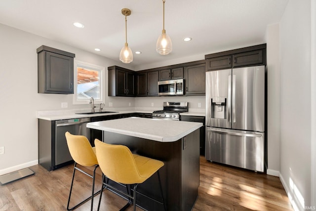 kitchen featuring appliances with stainless steel finishes, wood finished floors, a sink, and a center island