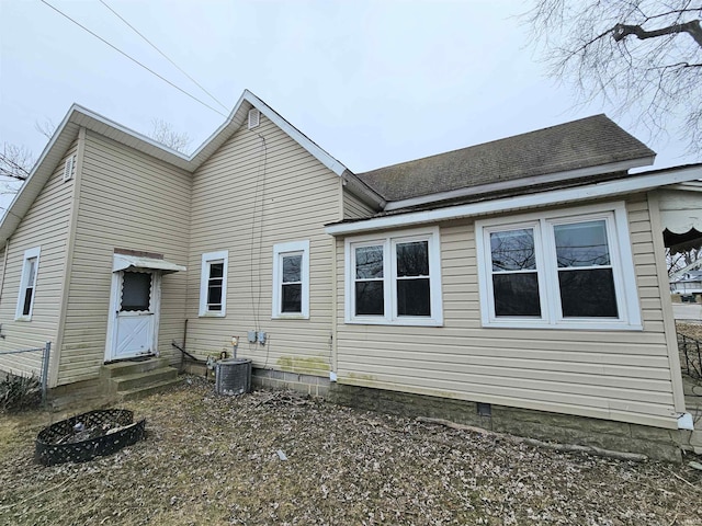 back of property featuring central AC unit and a fire pit