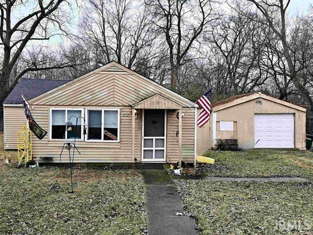 bungalow with a garage, an outdoor structure, and a front lawn