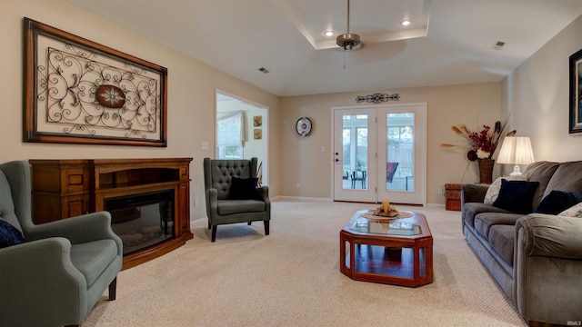 carpeted living room featuring a tray ceiling and ceiling fan