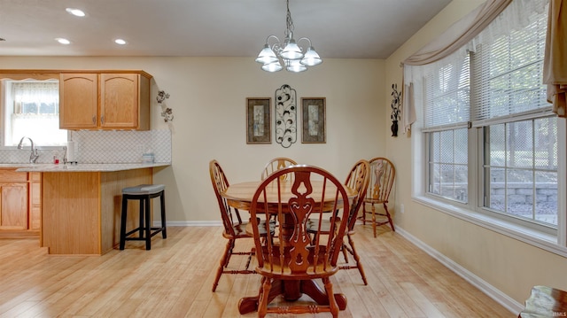 dining space featuring an inviting chandelier, sink, and light hardwood / wood-style flooring