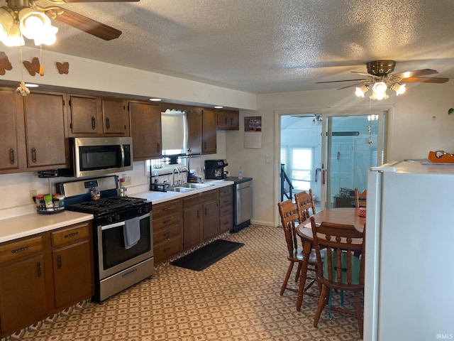 kitchen with stainless steel appliances, ceiling fan, sink, and a textured ceiling