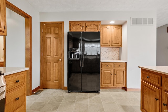 kitchen with backsplash, a textured ceiling, and black refrigerator with ice dispenser