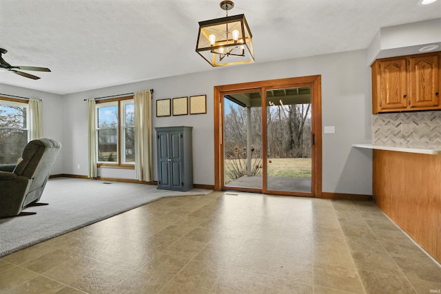 doorway to outside with ceiling fan with notable chandelier