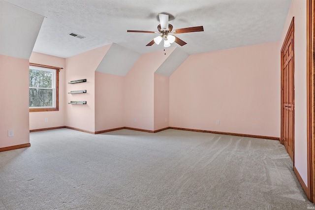 additional living space with ceiling fan, lofted ceiling, light carpet, and a textured ceiling