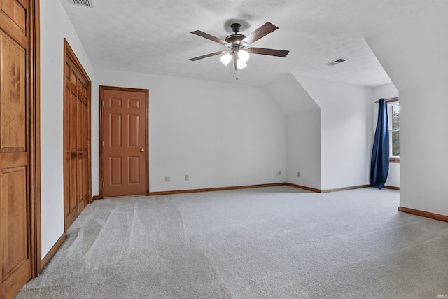 additional living space featuring ceiling fan, light colored carpet, and a textured ceiling