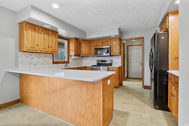 kitchen with sink, stainless steel appliances, tasteful backsplash, a textured ceiling, and kitchen peninsula