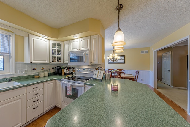 kitchen with hanging light fixtures, sink, white cabinets, and white appliances