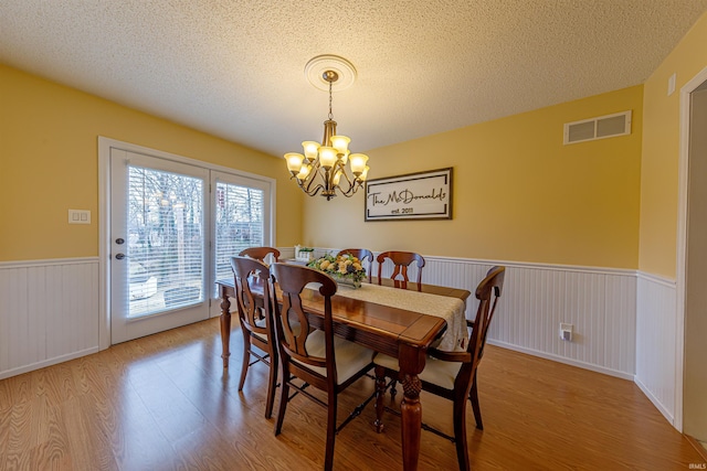 dining room with hardwood / wood-style flooring, an inviting chandelier, and a textured ceiling