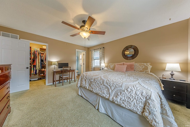 bedroom with ceiling fan, a walk in closet, light colored carpet, and a closet