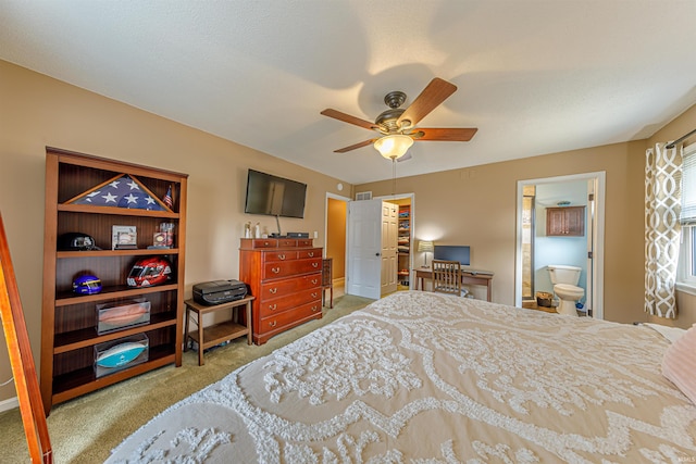 carpeted bedroom featuring ceiling fan, ensuite bathroom, and a walk in closet