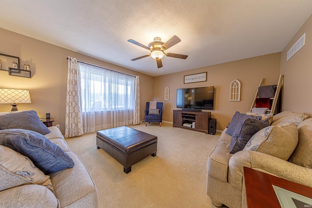 living room with ceiling fan, light carpet, and a textured ceiling